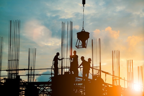 Silhouette of engineer and construction team working safely work load concrete on scaffolding on high rise building. over blurred background sunset pastel for industry background with Light fair
